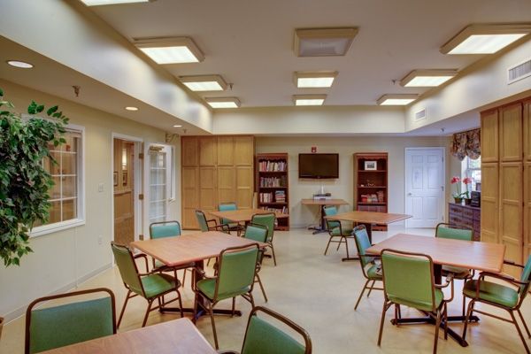 A modern conference room with tables, chairs, bookshelves, and a television.