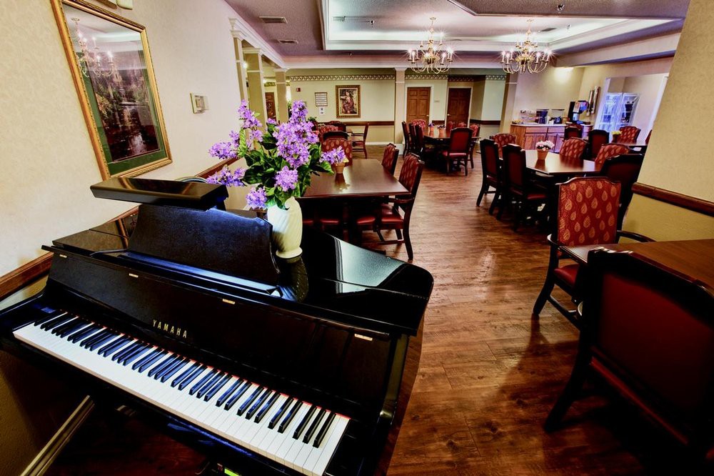 A cozy dining area with a piano and floral decorations.