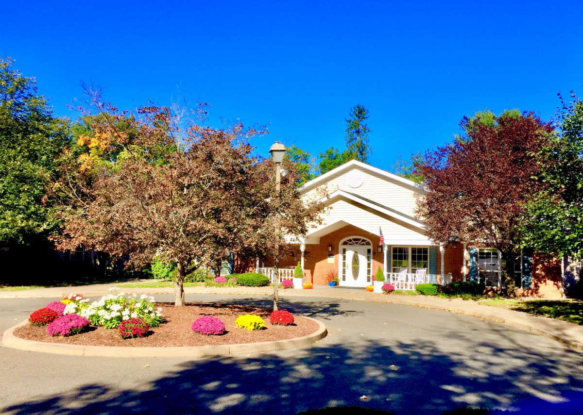 A charming house surrounded by well-maintained landscaping and vibrant flowers under a clear blue sky.