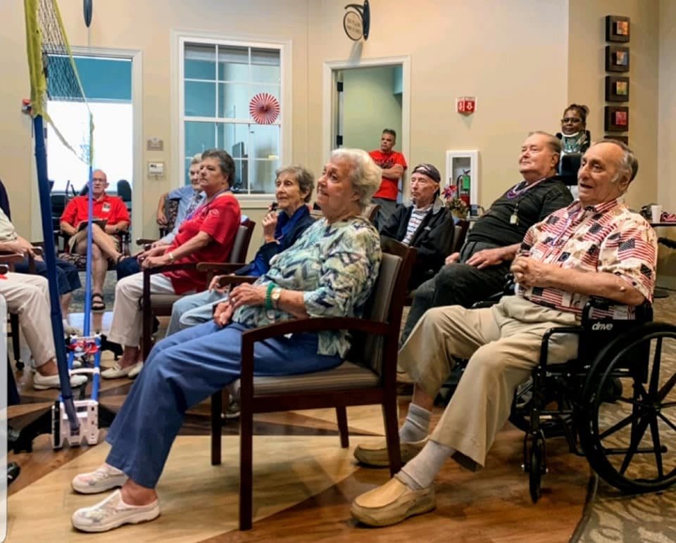 A group of seniors attending a community event indoors, seated and engaged.