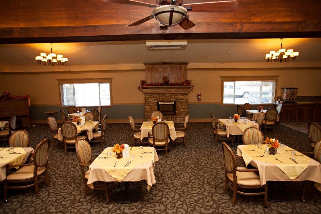 An elegant dining room with neatly arranged tables and a central fireplace.
