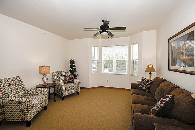 A cozy living room with comfortable seating, a ceiling fan, and soft lighting.