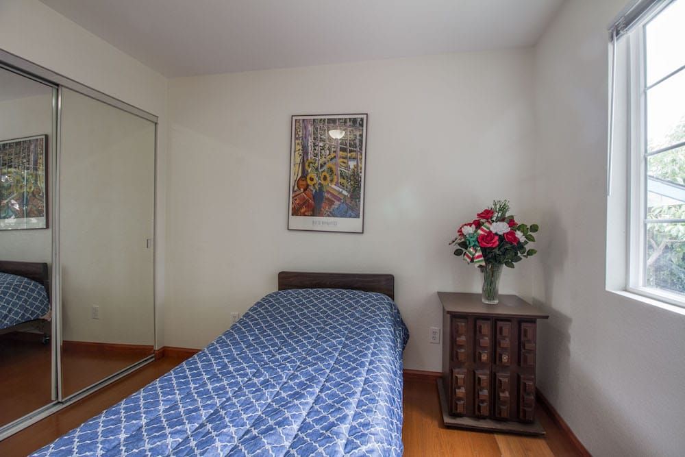 A simple bedroom with a single bed and floral decorations.