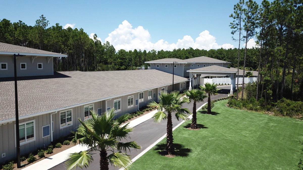 A residential building surrounded by palm trees and a clear blue sky.