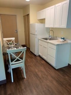A compact kitchen and dining area with white cabinets and wooden flooring.