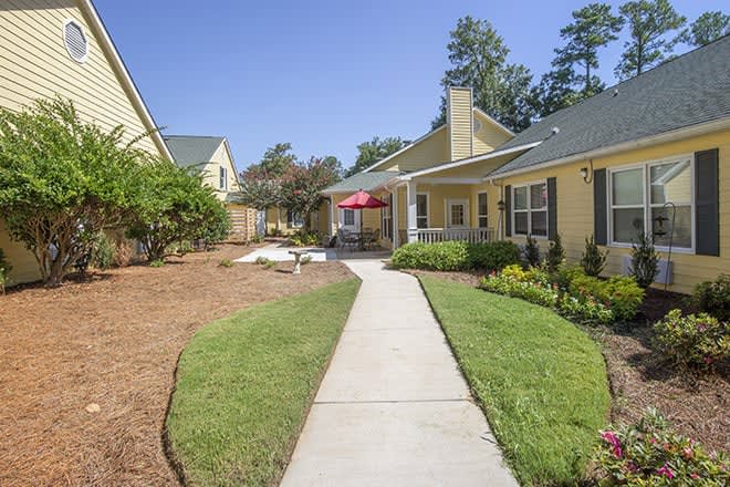 A walkway leading through a well-maintained residential yard with houses and landscaping.