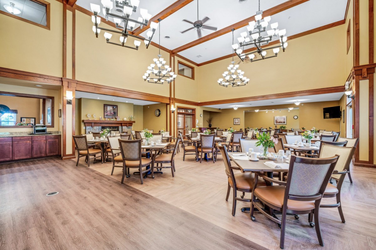 A spacious and elegantly decorated dining room with multiple tables and chandeliers.