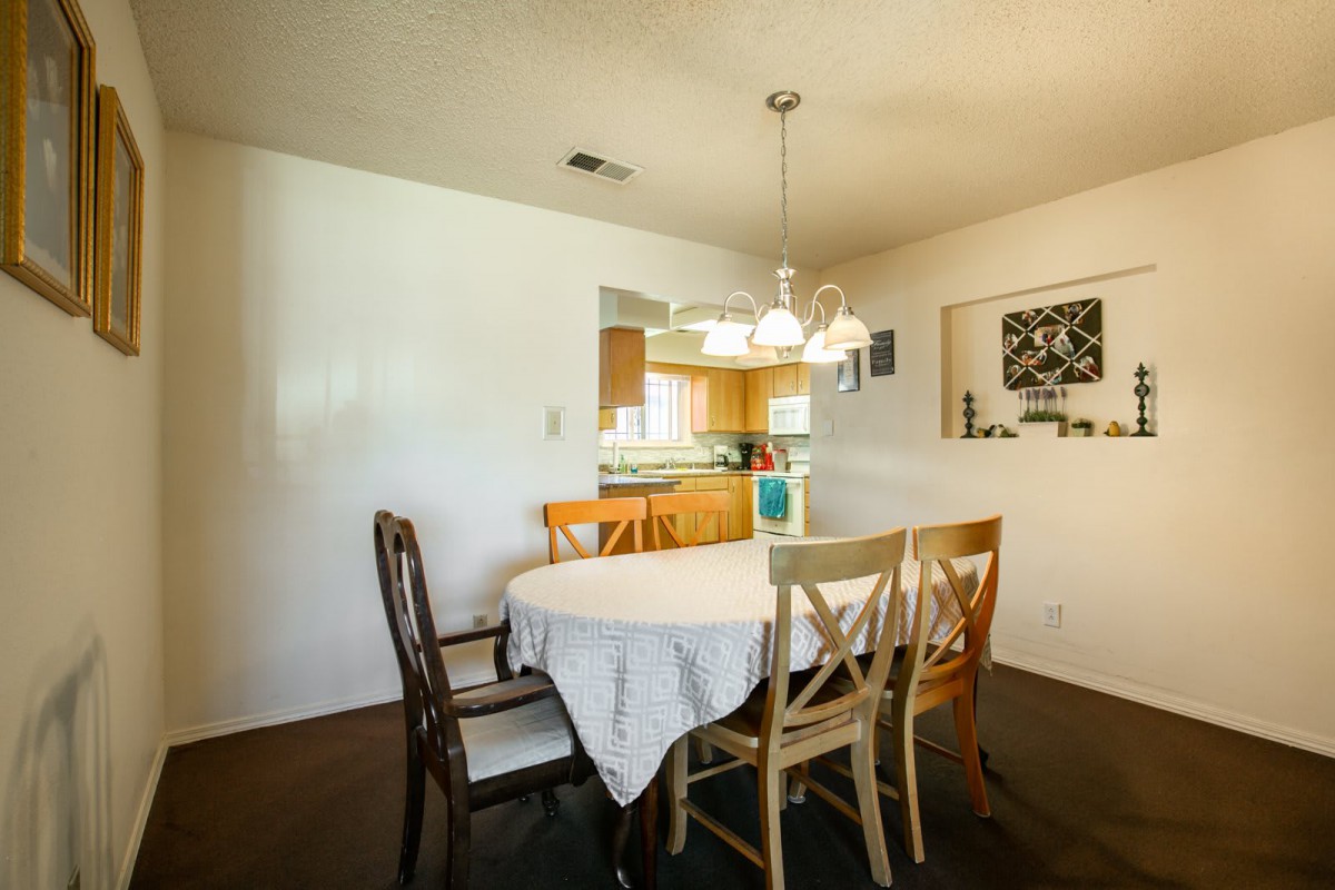 A cozy dining area with a round table and mixed chairs, adjacent to a kitchen.