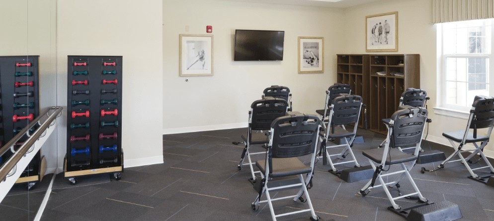 An empty conference room with neatly arranged chairs facing a mounted television and artwork on the walls.