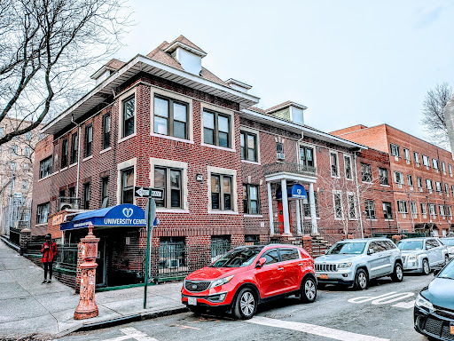 A red car parked in front of a brick building on a city street.