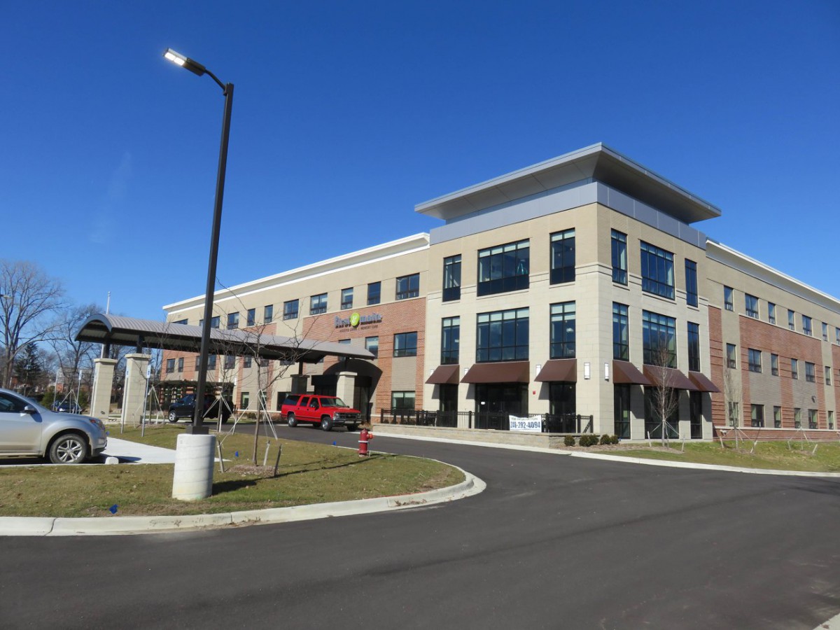 A modern office building with large windows and a parking area.