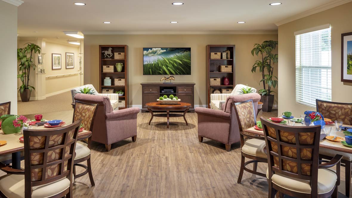 A cozy living room with comfortable seating, a wall-mounted television, and decorative shelves.