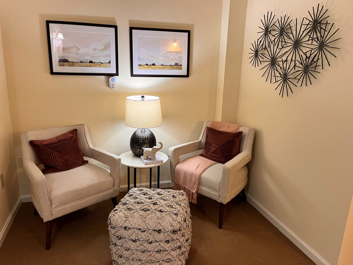 A cozy living room corner with two armchairs, a lamp, and wall art.