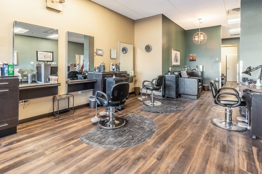 A modern hair salon interior with styling stations and mirrors on a wooden floor.