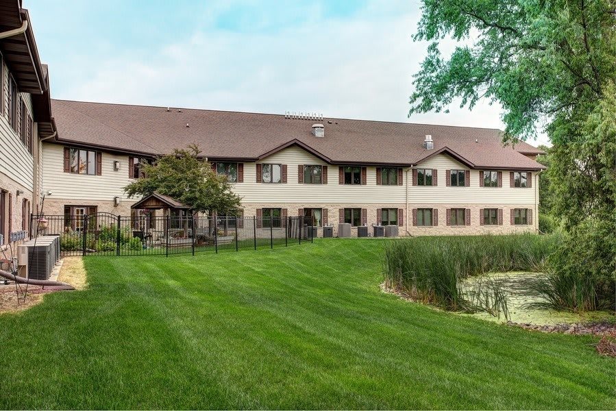 A two-story residential building with a well-maintained lawn and surrounding greenery.