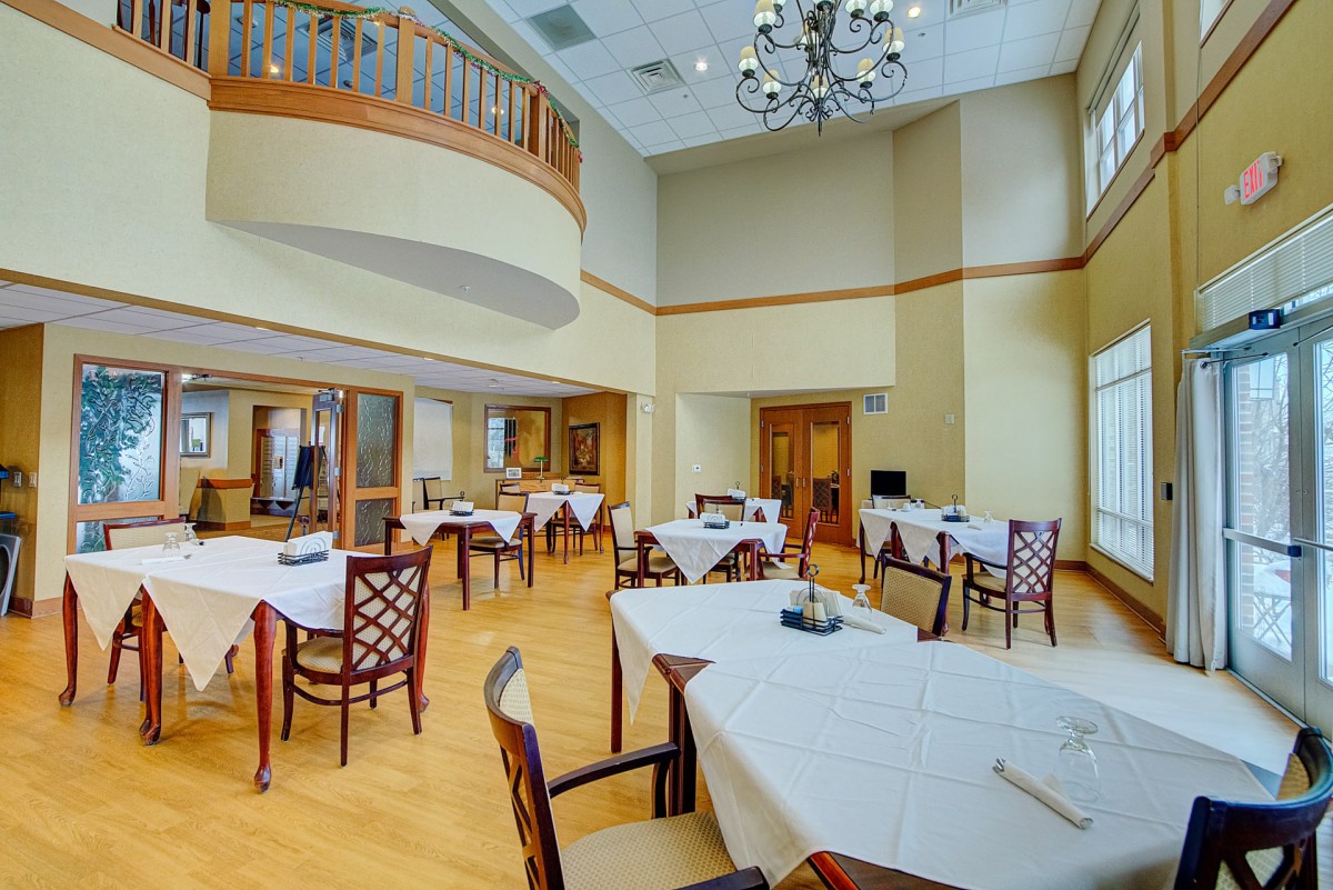 An elegant and spacious dining room with neatly arranged tables and chairs under a chandelier.