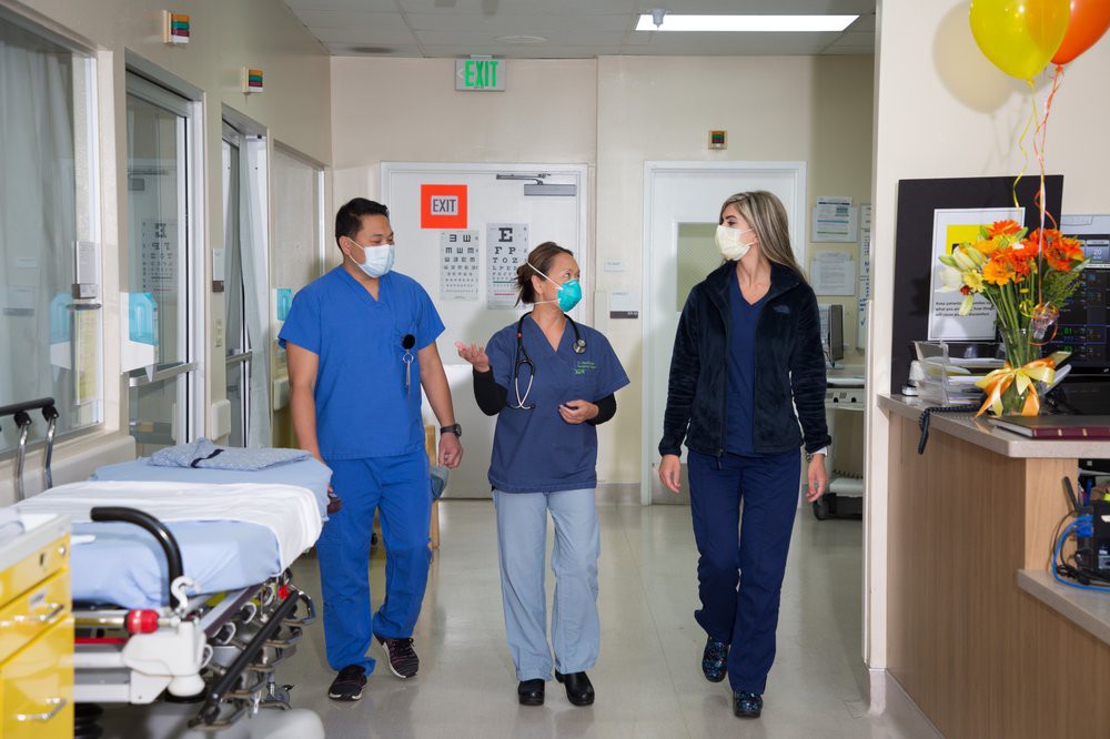 Medical professionals walking and discussing in a hospital corridor.