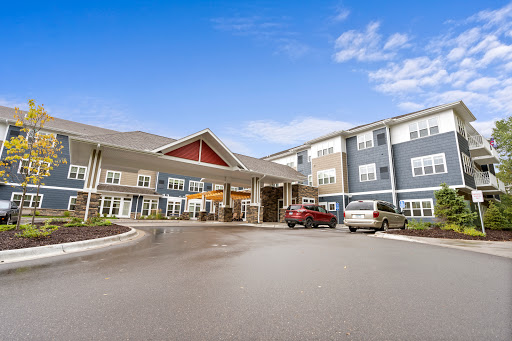 A welcoming view of a modern residential complex with a spacious entrance and outdoor parking under a clear blue sky.