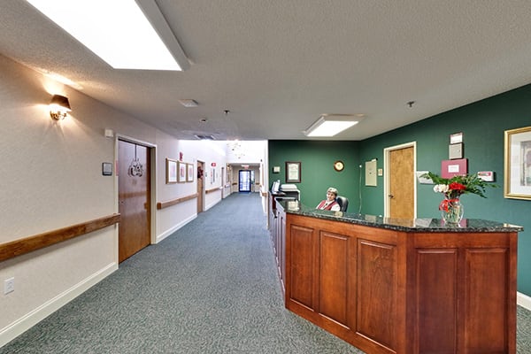 A reception desk in an office hallway with green walls and carpeted flooring.