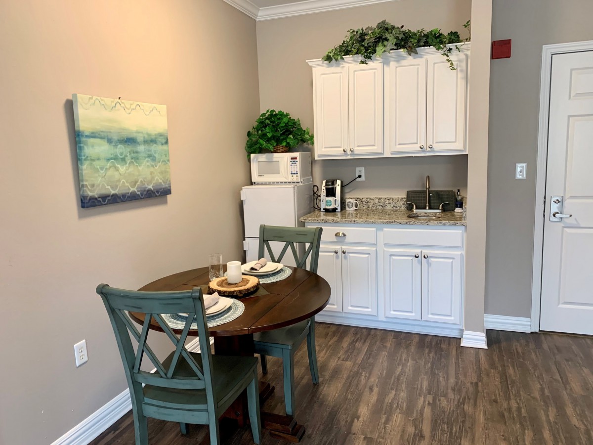 Cozy kitchen corner with a small dining table and chairs, white cabinets, and decorative accents.