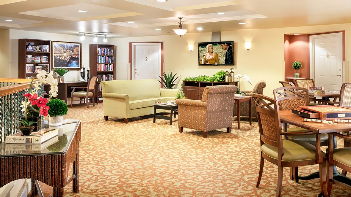 A cozy and well-furnished living room with a sofa, chairs, and a library area.
