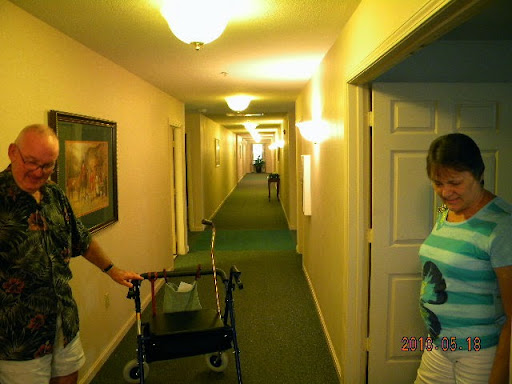 An elderly person using a walker in a well-lit hallway.