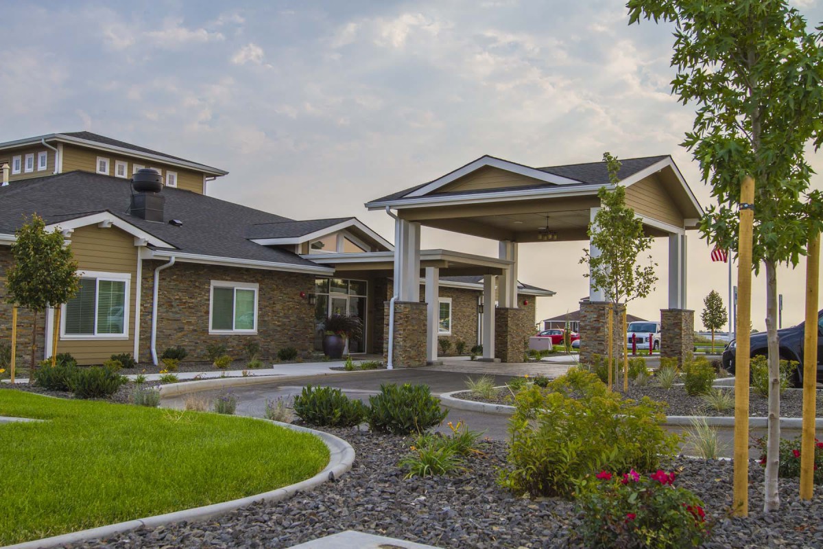 A modern residential building with a landscaped entrance and overcast sky.