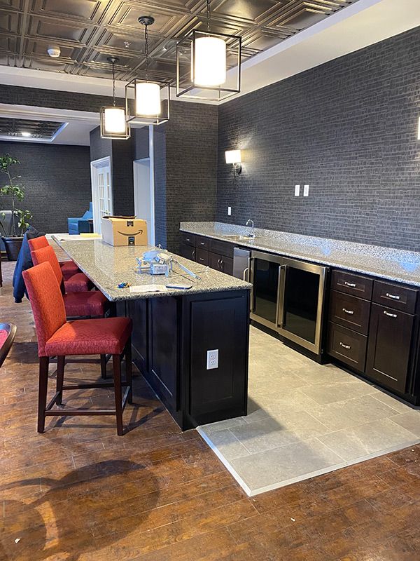 A modern kitchen interior with a long countertop, red bar stools, and sleek cabinets.