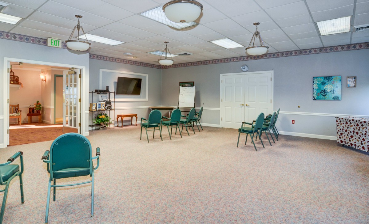A spacious meeting room with chairs arranged in a circle, featuring a television and a flip chart.