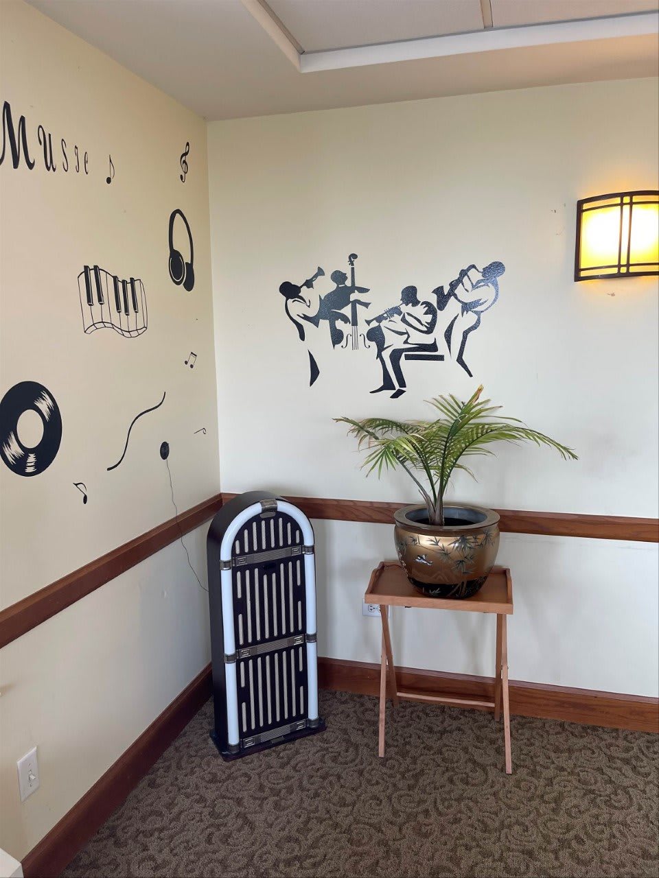 A retro-themed corner with wall art of musicians, vinyl records, a jukebox, and an indoor plant.