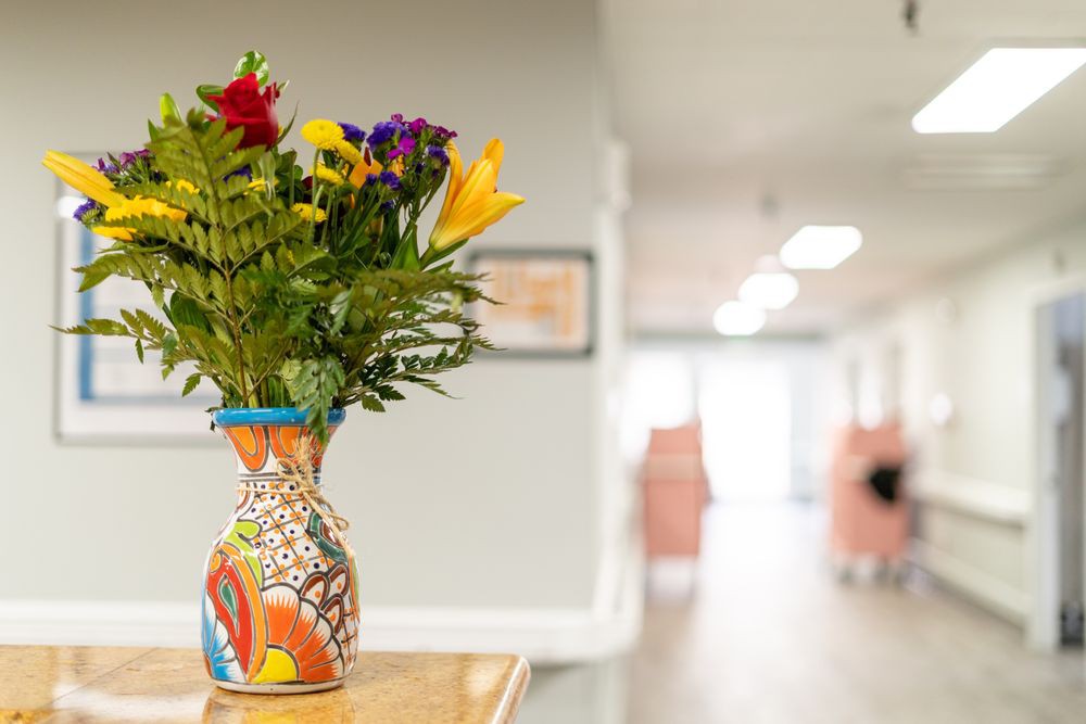 A colorful bouquet of flowers in an artistic vase brightens up a hallway.