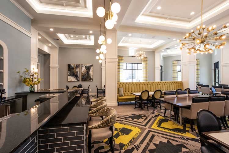 A stylish and modern lounge with a mix of seating options, featuring elegant chandeliers and contemporary artwork.
