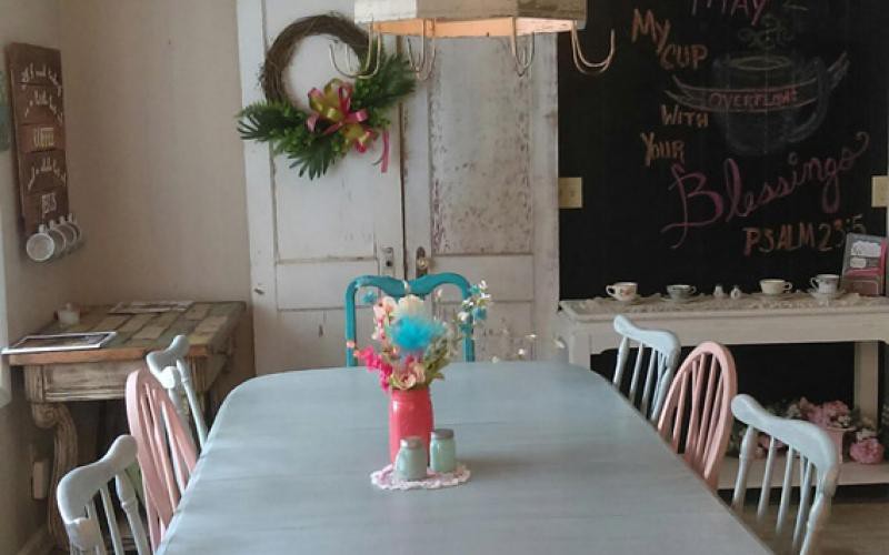 A cozy dining area with a decorated table centerpiece and a festive wreath on the wall.
