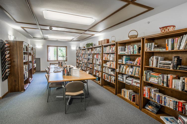 A quiet library room with shelves filled with books and tables for reading.