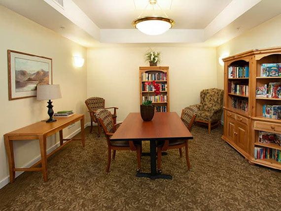 A cozy meeting room with bookshelves, a rectangular table, and comfortable chairs.