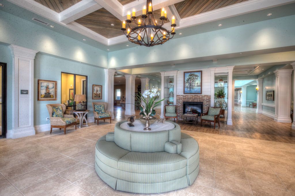 A spacious and elegant living room featuring a central round sofa, a chandelier, and tasteful decor.
