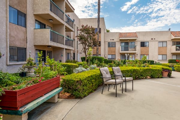 A well-maintained apartment complex with outdoor seating and lush landscaping.
