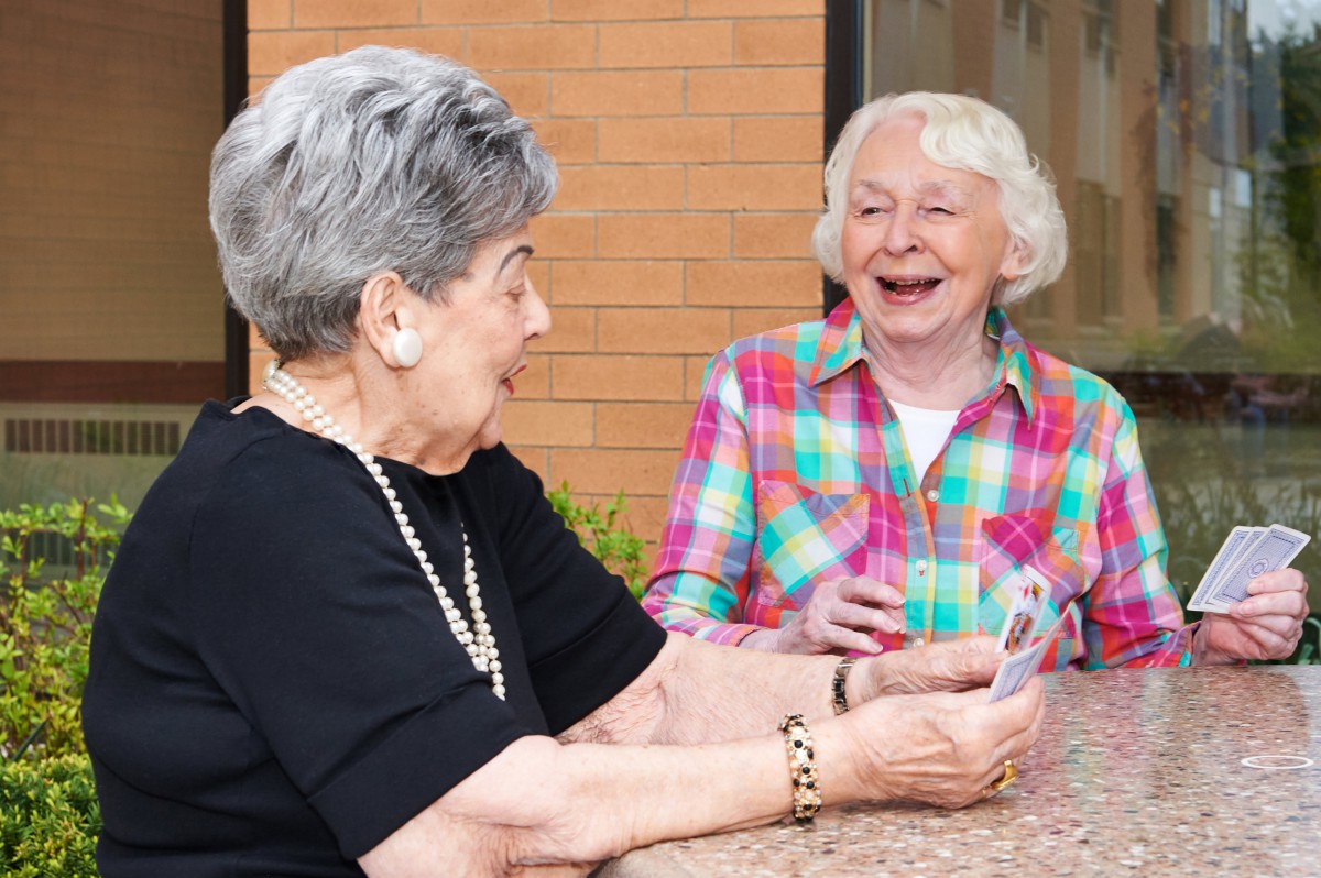 Two senior women enjoying a conversation outdoors.