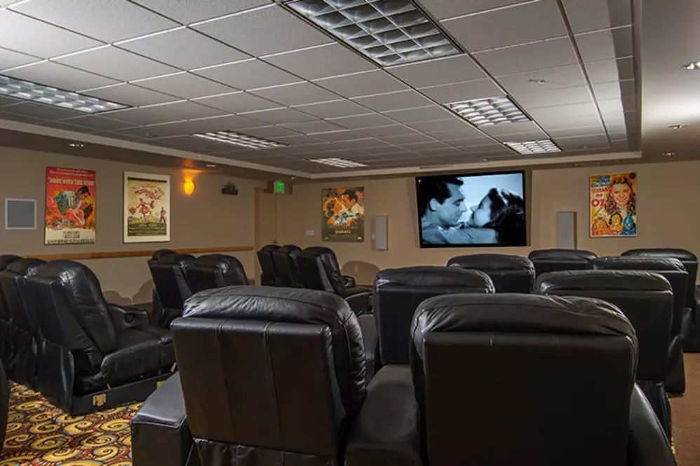 A cozy home theater with multiple leather seats facing a large screen.