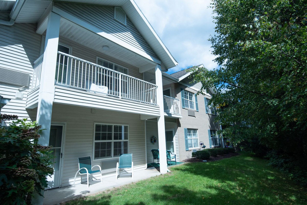 A two-story residential building with a balcony and lawn area.