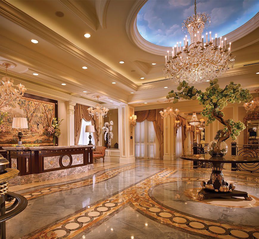 A lavish hotel lobby featuring a grand chandelier and intricate marble flooring.