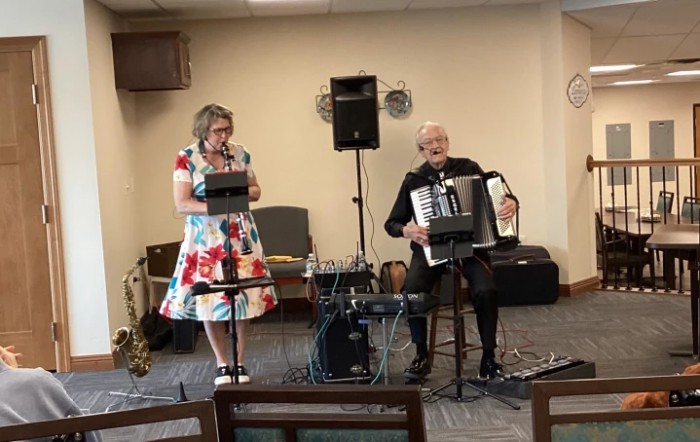 A duo performing with an accordion and microphone in an indoor setting.