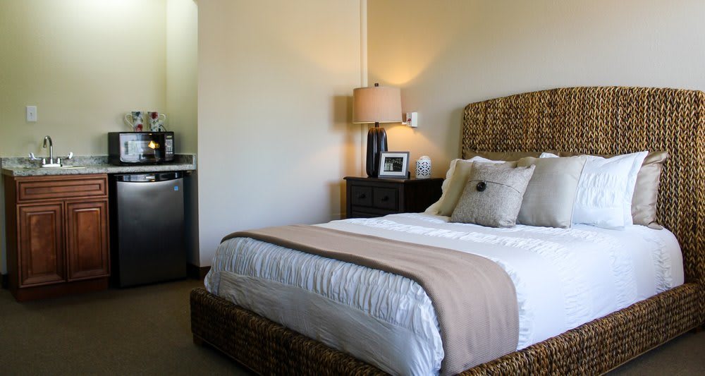 A cozy bedroom with a neatly made bed, stylish lamp, and elegant decor.