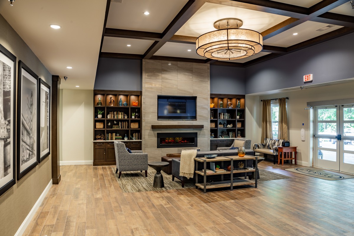 A modern living room with a fireplace, elegant chandelier, and comfortable seating.