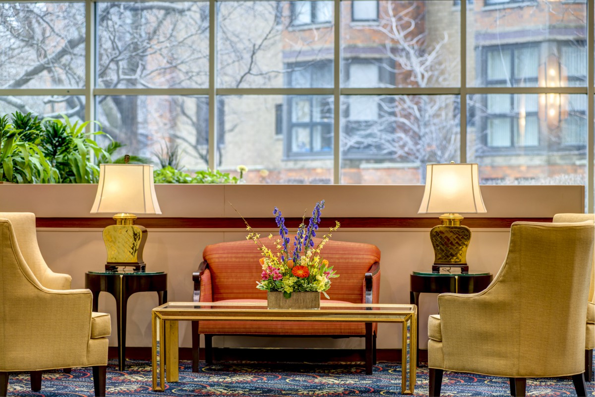 A cozy lobby area with comfortable seating, decorative lamps, and a floral centerpiece on a table.