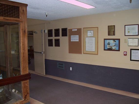 A hallway with plaques and a bulletin board on the wall.