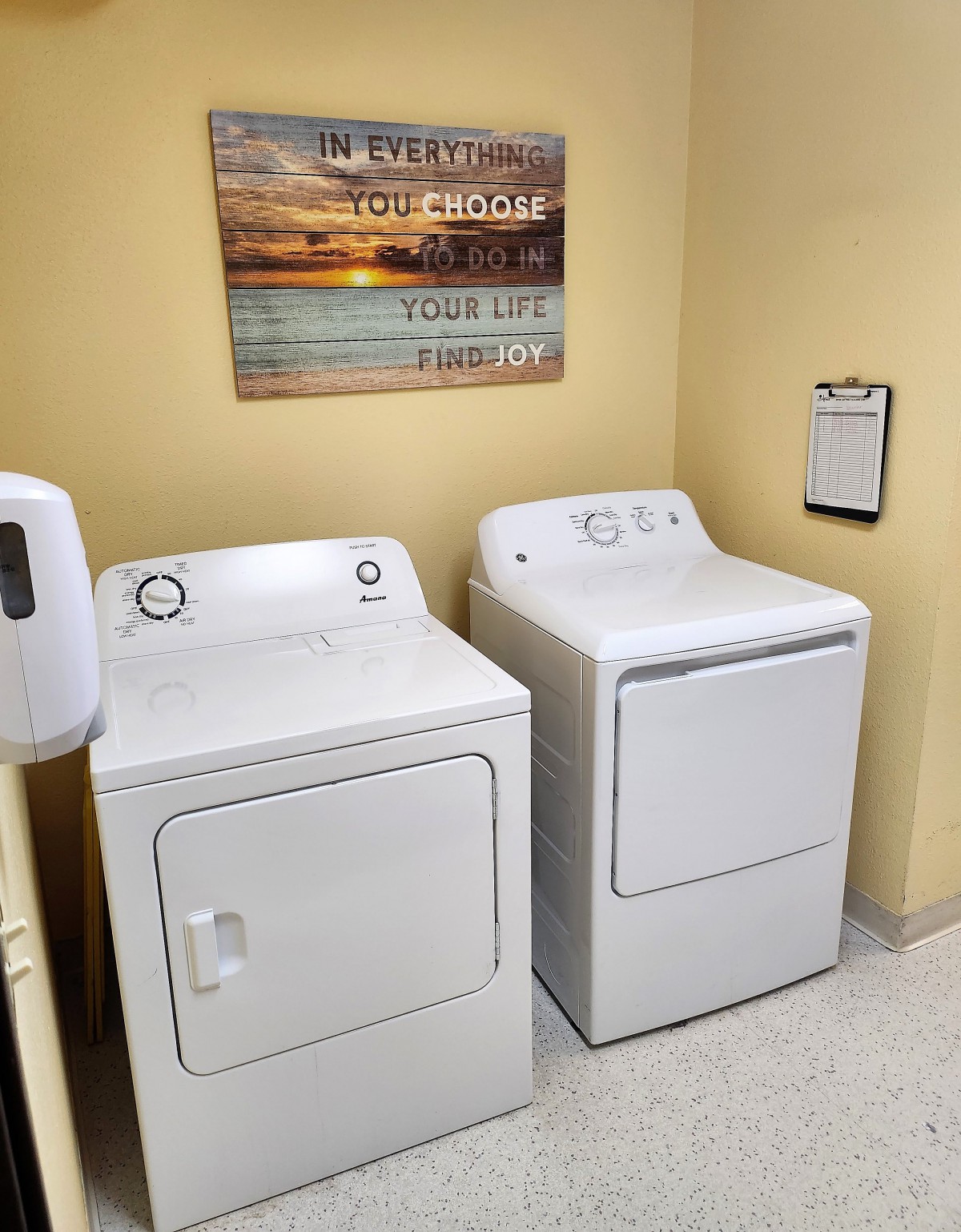 A tidy laundry room featuring a washer and dryer set under a motivational wall art.