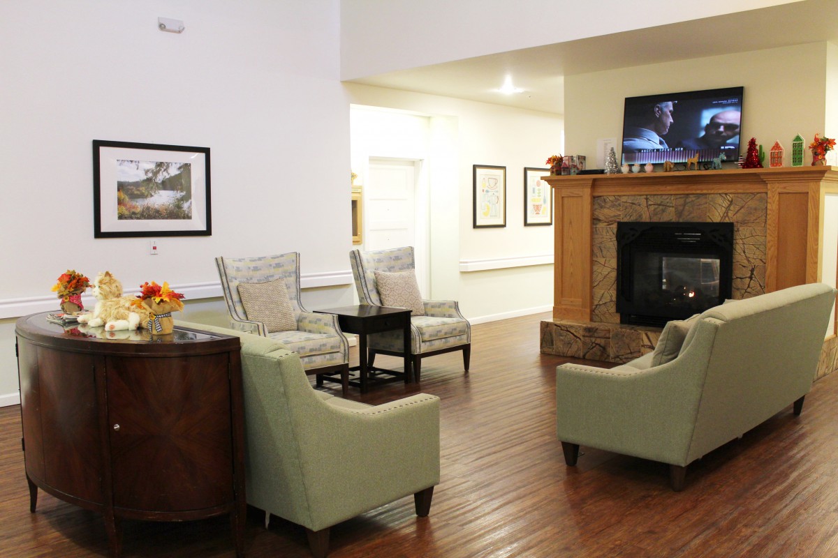 A cozy living room with a fireplace, comfortable seating, and a wall-mounted television.