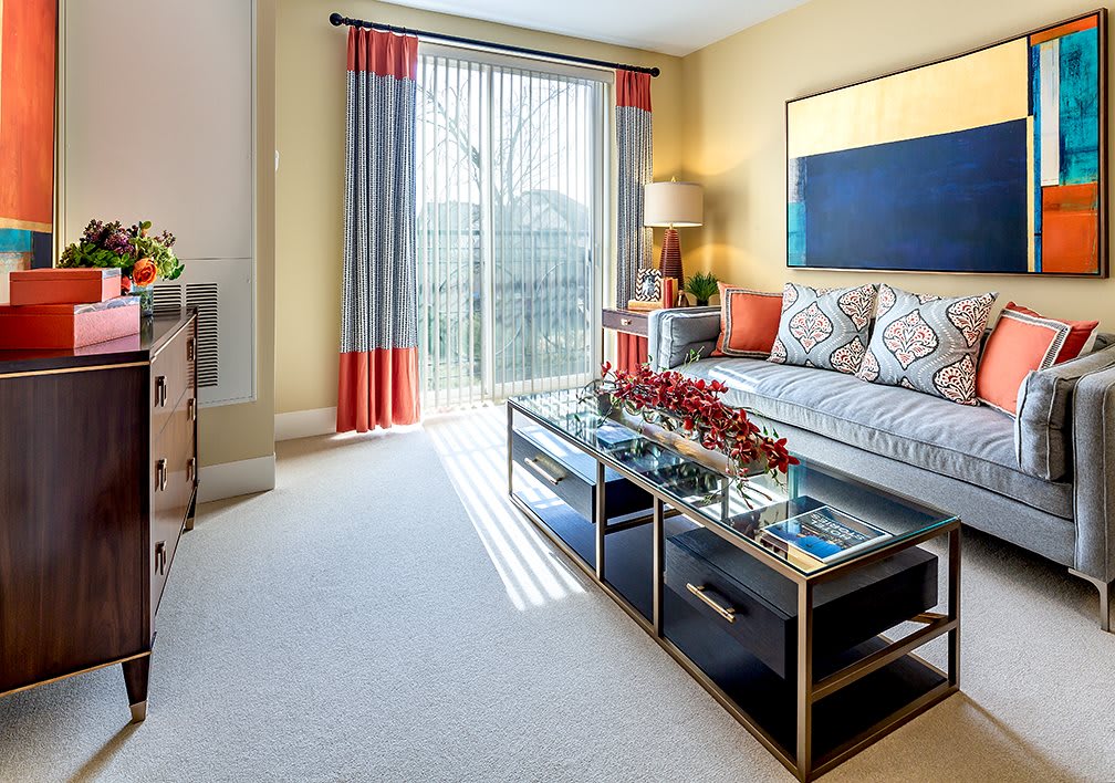 A modern living room with a glass coffee table and colorful curtains.