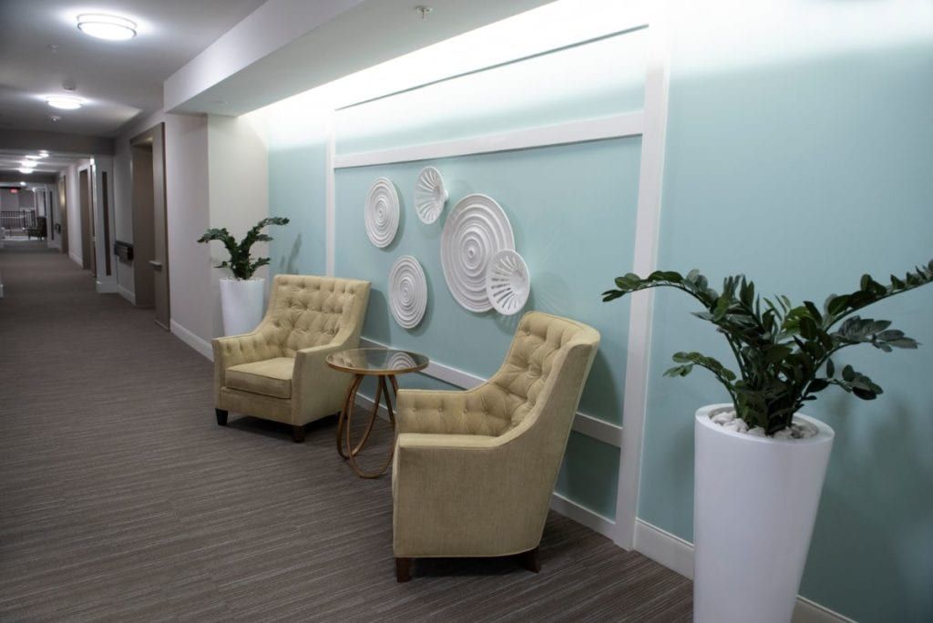 A cozy lobby seating area with two tufted chairs and decorative wall art.